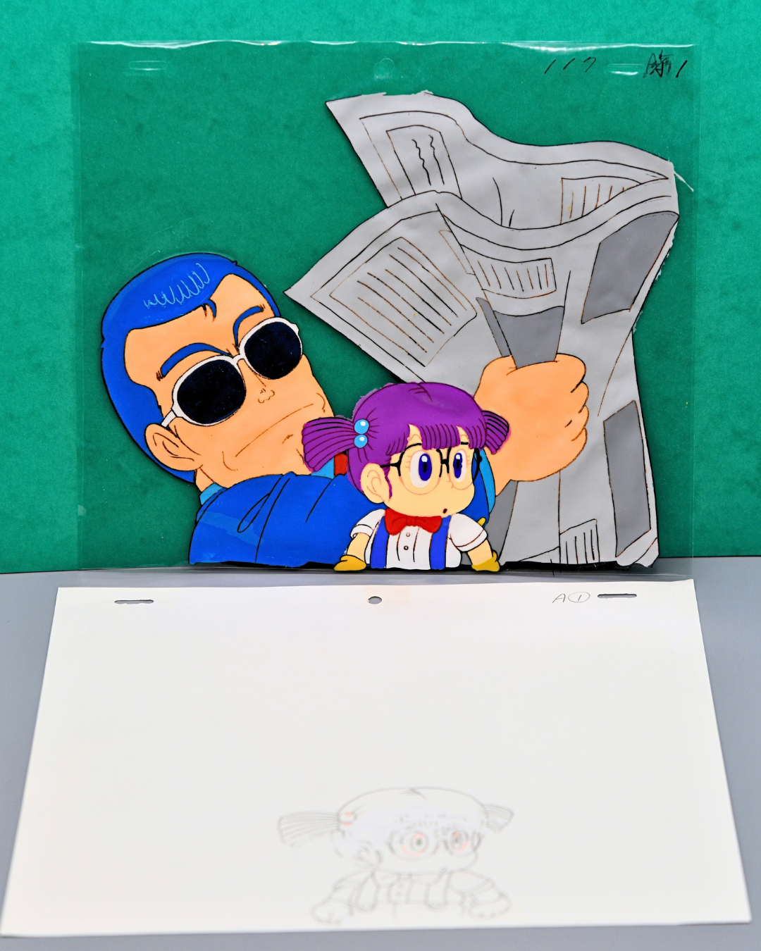 Dr. Slump Arale and Suppaman original multi-layer production cel, Suppaman reading newspaper